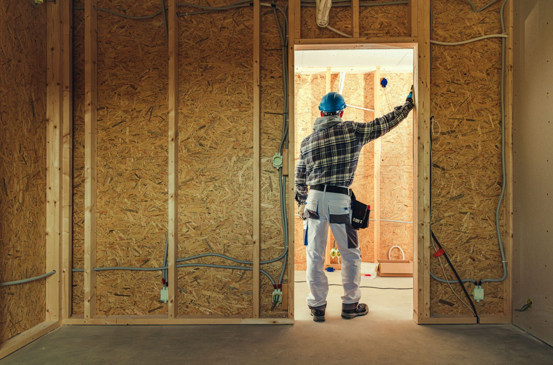Construction worker leaning against door frame of interior room in house being built.